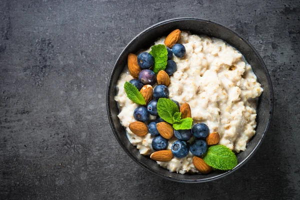 Oatmeal porridge with fresh berries and nuts top view. — Stock Photo, Image