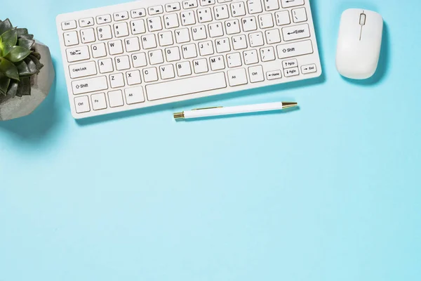 Bureau avec clavier et ordinateur portable sur fond bleu . — Photo