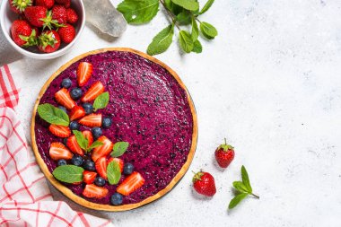 Beyaz masa üst görünümünde berry cheesecake.