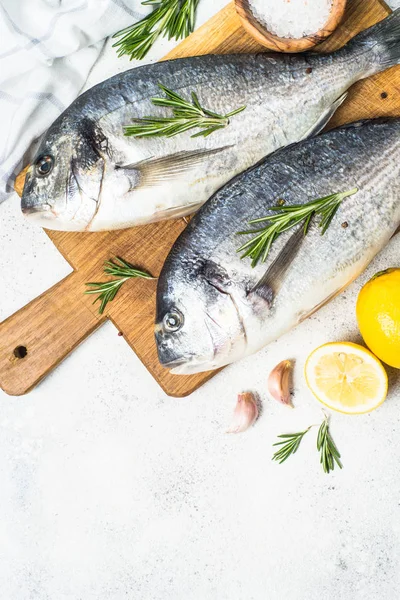 Poisson dorado cru sur la planche à découper sur la table . — Photo