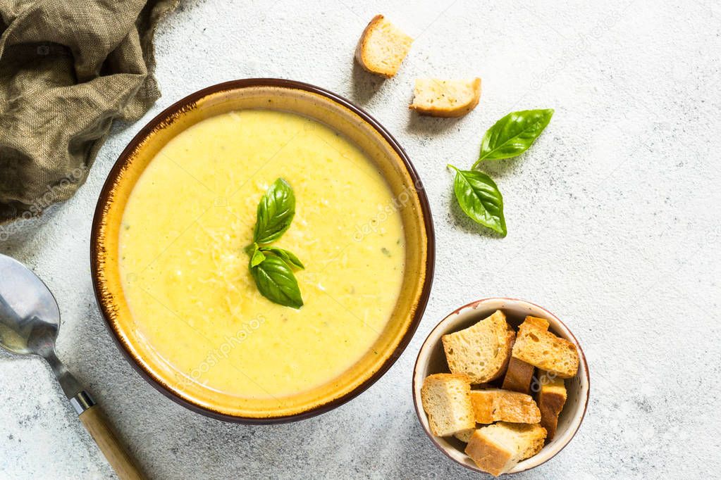 Zucchini Cream soup with basil and croutons on white.