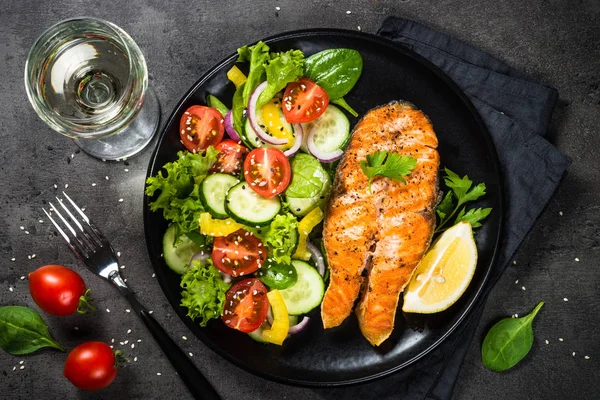 Grilled salmon fish steak with vegetables on black. — Stock Photo, Image