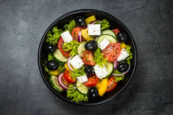 Greek salad in black plate on the table.