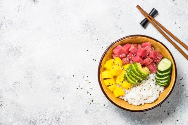 Beyaz masada pirinç, avokado, mango ve salatalık ile tuna poke kase.