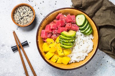 Beyaz masada pirinç, avokado, mango ve salatalık ile tuna poke kase.