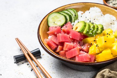 Beyaz masada pirinç, avokado, mango ve salatalık ile tuna poke kase.