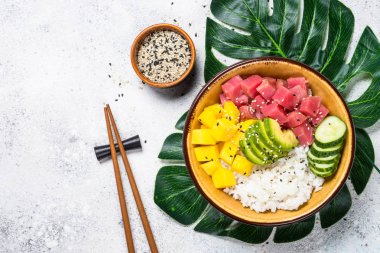 Beyaz masada pirinç, avokado, mango ve salatalık ile tuna poke kase.