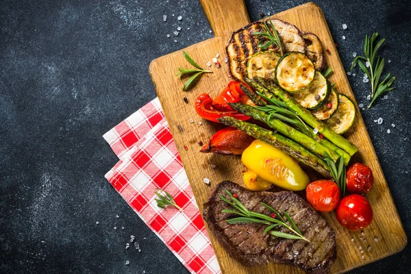 Bistecca di manzo alla griglia con verdure sul tavolo di pietra nera . — Foto Stock