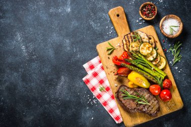 Sığır eti biftek siyah taş masada sebze ile ızgara.