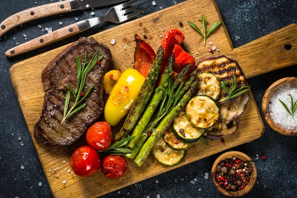 Marha steak grillezett zöldségekkel, fekete kőasztal. — Stock Fotó