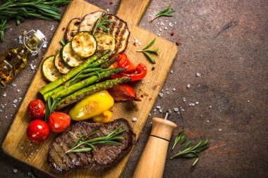 Dana biftek kesme tahtası üzerinde sebze ile ızgara