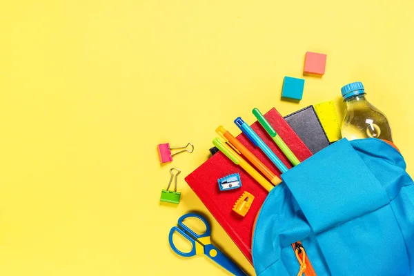 Zaino scuola con cancelleria su sfondo giallo . — Foto Stock