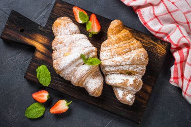 Siyah arka plan üzerinde taze çilek ile Kruvasan.