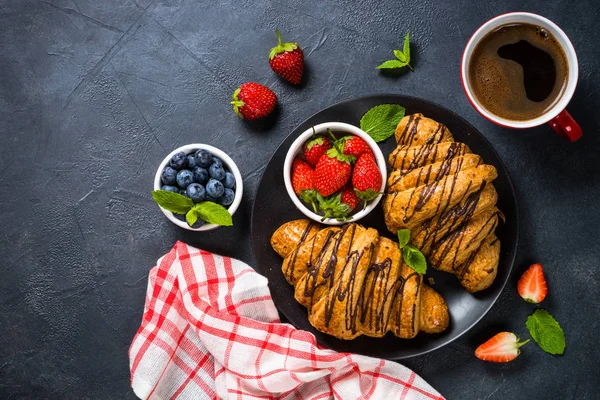 Croissant with fresh berries and cup of coffee on black. — Stock Photo, Image