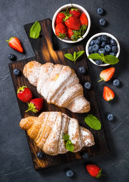 Croissant con bacche fresche su sfondo nero . — Foto Stock