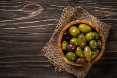 Ahşap masada siyah ve yeşil zeytin.