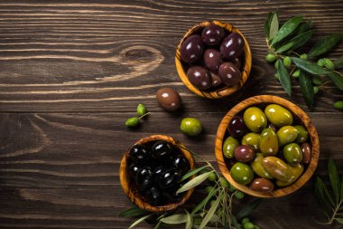 Ahşap masada siyah ve yeşil zeytin.