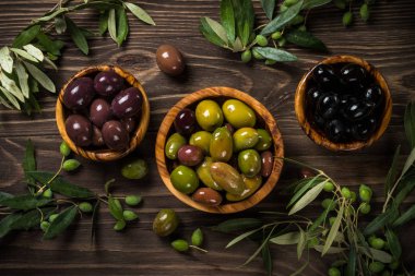 Ahşap masada siyah ve yeşil zeytin.