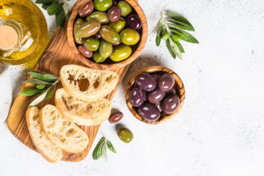 Beyaz arka planda zeytin, ciabatta ve zeytinyağı.