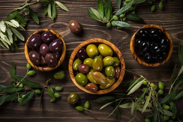 Aceitunas negras y verdes sobre mesa de madera. —  Fotos de Stock