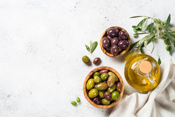 Olives in wooden bowls and olive oil bottle on white background.