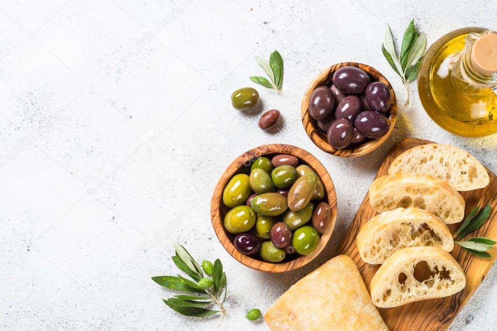 Olives, ciabatta and olive oil on white background.