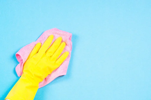 Hand in yellow gloves and microfiber rag cleaning blue background. — Stock Photo, Image