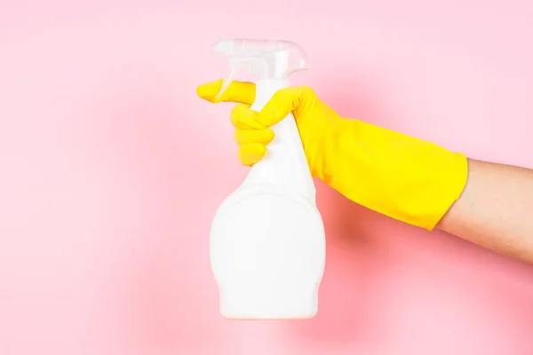 Mano en guantes amarillos sostener botella agente de limpieza sobre fondo rosa . —  Fotos de Stock