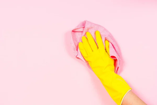 Mano in guanti gialli e microfibra straccio pulizia sfondo rosa . — Foto Stock