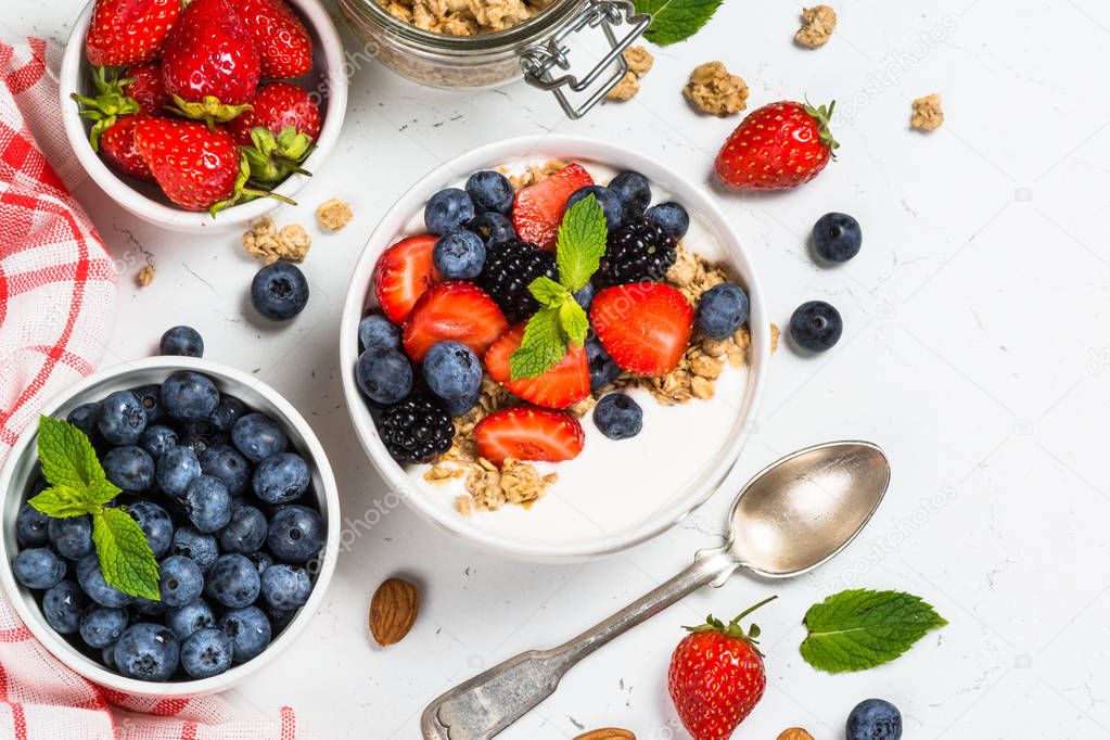 Greek yogurt granola with fresh berries on white table.