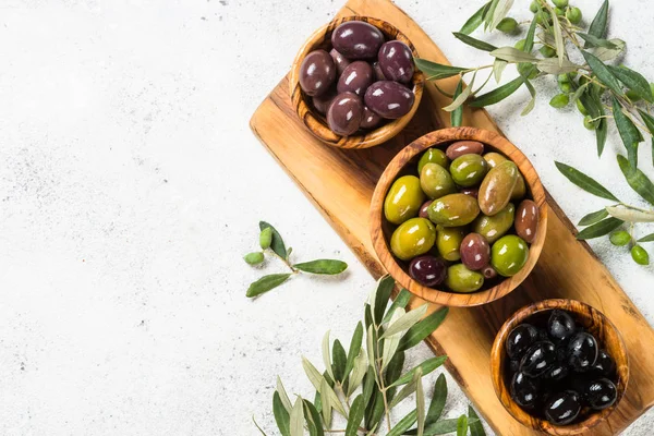 Natural greek Olives in wooden bowls and olive oil bottle on white background. — Stock Photo, Image