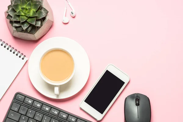 Posto di lavoro ufficio con blocco note, tazza di caffè e tastiera su sfondo rosa . — Foto Stock