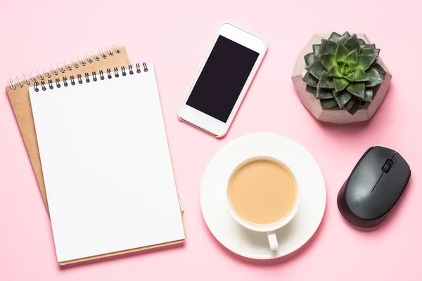 Freelance workplace with notepad, coffee cup, succulent and mouse on pink