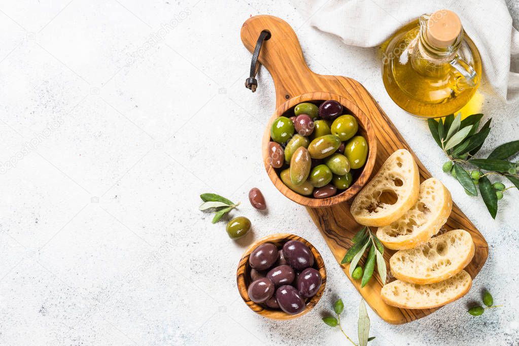 Olives, ciabatta and olive oil on white background.