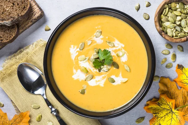 Pumpkin cream soup on light stone table.