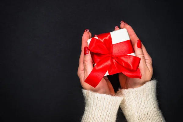 Vrouw geeft een cadeau op zwarte achtergrond. — Stockfoto