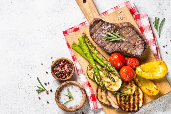 Bife de carne grelhado com legumes na mesa de pedra branca . — Fotografia de Stock