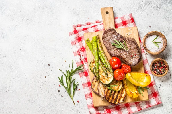 Grillezett húsok zöldségekkel, fehér kőasztalon. — Stock Fotó