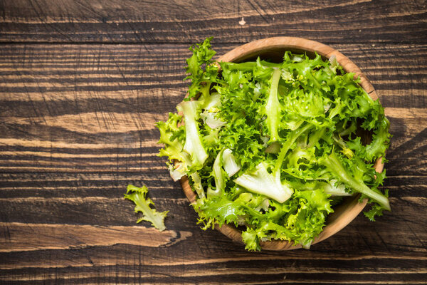 Green salad frieze on dark wooden table.