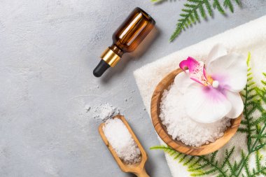 Gri taş zemin üzerinde deniz tuzu ve kozmetik yağ.