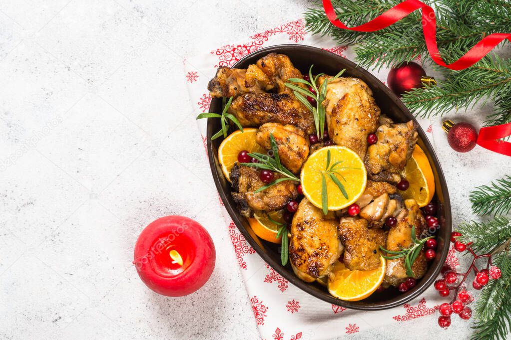 Christmas food - roasted chicken with orange on white table.