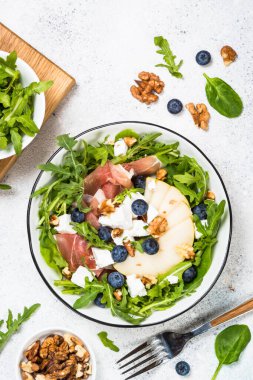 Yapraklı yeşil salata, meyve ve jamon.