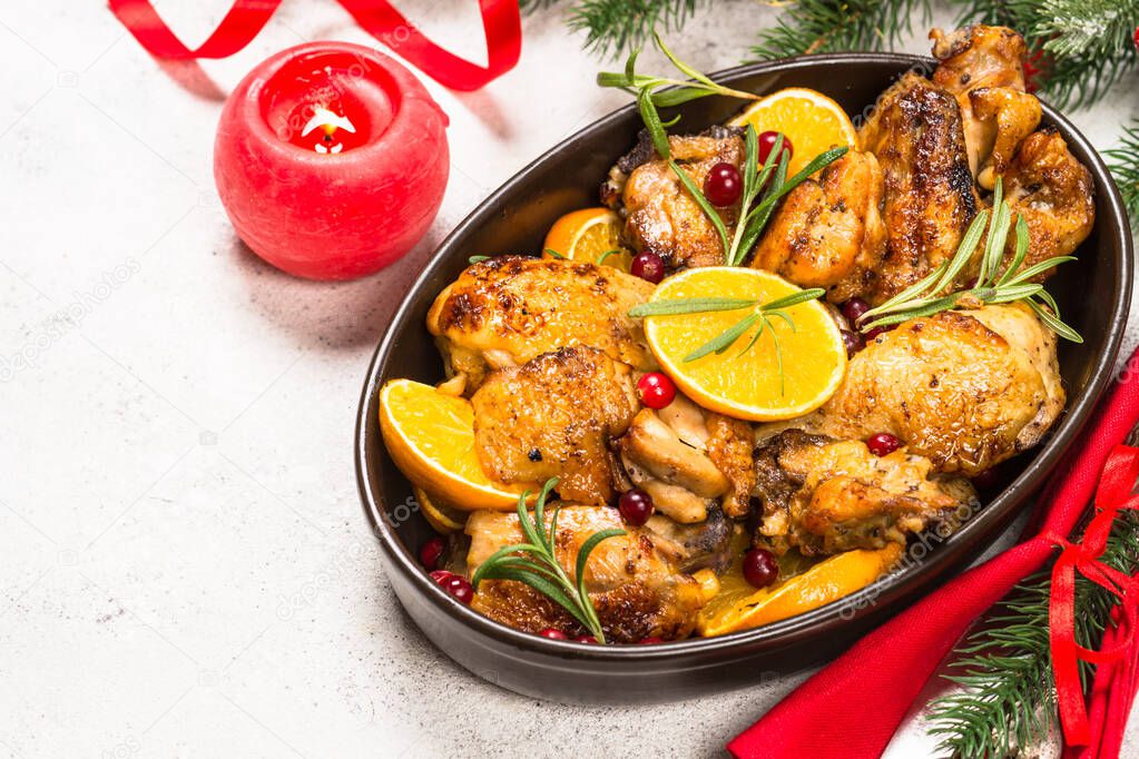 Christmas food - roasted chicken with orange on white table.
