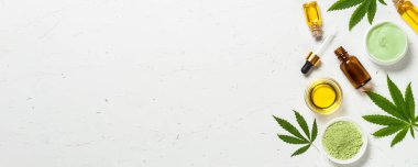 Kenevir yağı ve yeşil yapraklar beyaz masada.