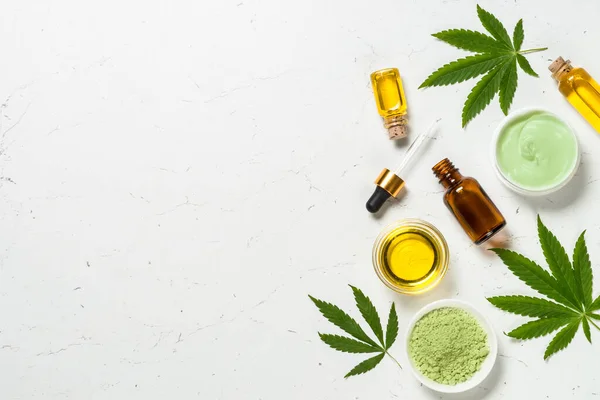 Cannabis oil and green leaves at white table. — Stock Photo, Image