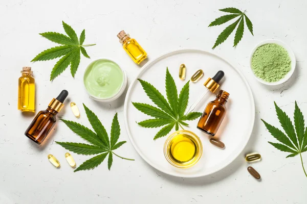 Cannabis oil and green leaves at white table. — Stock Photo, Image