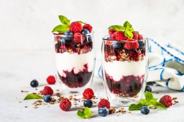 Parfait with granola, jam and fresh berries in the glass jar.