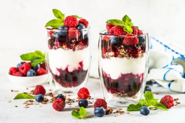 Parfait with granola, jam and fresh berries in the glass jar.