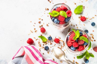 Parfait with granola, jam and fresh berries in the glass jar.