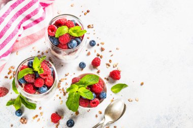 Parfait with granola, jam and fresh berries in the glass jar.